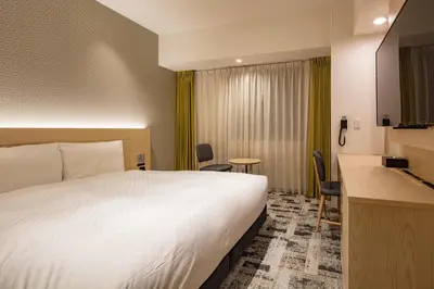 a hotel room with a white bed and a desk at Via Inn Prime Nihonbashi Ningyocho in Tokyo