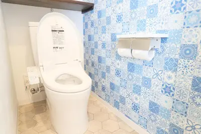 a bathroom with a toilet with blue and white tiles at Villa Ikebukuro in Tokyo