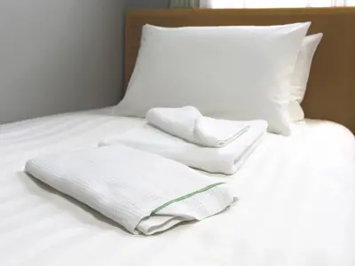a pile of towels sitting on top of a bed at Business Hotel Sunpalace in Tokyo