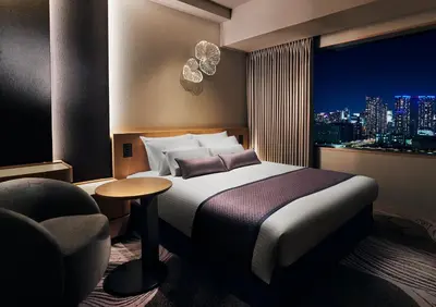 a hotel room with a bed and a chair and a window at Hotel JAL City Tokyo Toyosu in Tokyo