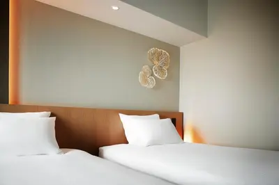 two beds with white sheets and a butterfly on the wall at Hotel JAL City Tokyo Toyosu in Tokyo