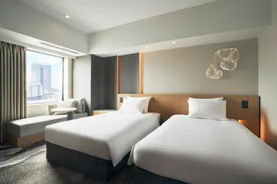 a hotel room with two beds and a chair at Hotel JAL City Tokyo Toyosu in Tokyo