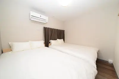 two beds in a room with white sheets at ACT one in Tokyo