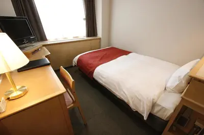 a hotel room with a bed and a desk with a lamp at Hotel Abest Meguro in Tokyo