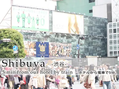 a crowd of people walking down a street with a billboard at Hotel Abest Meguro in Tokyo