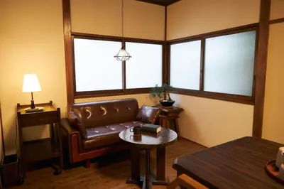 a living room with a leather couch and a table at Kagurazaka Retro BAR & HOTEL in Tokyo