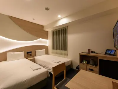 a hotel room with two beds and a table at Henn na Hotel Premier Tokyo Asakusa Tawaramachi in Tokyo