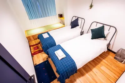 two twin beds in a small room with wooden floors at Skytree Tatami Hotel in Tokyo