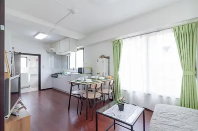 a living room with a kitchen and a table with chairs at Uhome Iriya Apartment in Tokyo