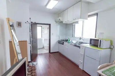 a white kitchen with a sink and a microwave at Uhome Iriya Apartment in Tokyo
