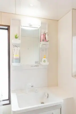 a white bathroom with a sink and a mirror at Uhome Iriya Apartment in Tokyo