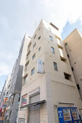 a tall white building in a city at Uhome Iriya Apartment in Tokyo