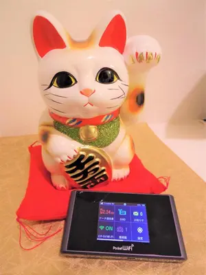 a toy cat sitting on a red pillow next to a tablet at ☆Cozy Japanese style room☆ in Tokyo