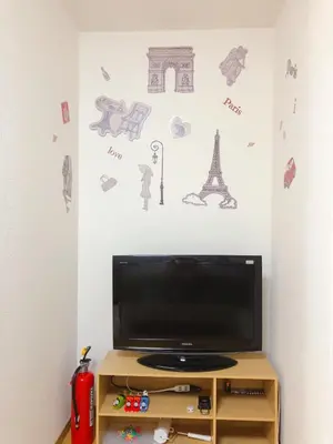 a television in a room with a wall with drawings on it at C.H.House in Tokyo
