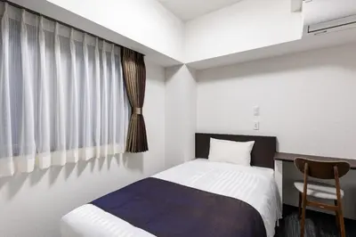 a bedroom with a bed and a chair and a window at Shinbashi Urban Hotel in Tokyo