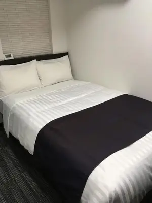 a bedroom with a large bed with white and black sheets at Shinbashi Urban Hotel in Tokyo