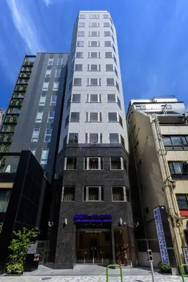 a tall white building in front of two tall buildings at Shinbashi Urban Hotel in Tokyo