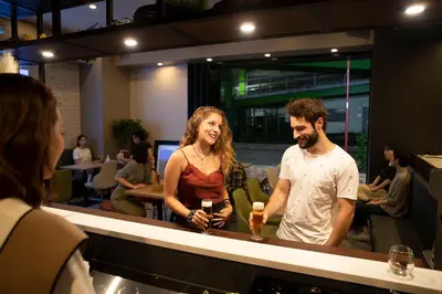 a man and woman standing at a bar with drinks at Grids Tokyo Ueno Hotel&Hostel in Tokyo