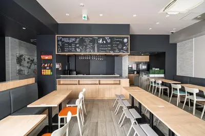 a restaurant with wooden tables and chairs and a chalkboard at Grids Tokyo Ueno Hotel&Hostel in Tokyo