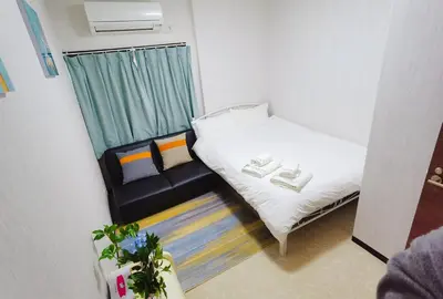 a small room with a bed and a couch at Mitsuba Guest House in Tokyo