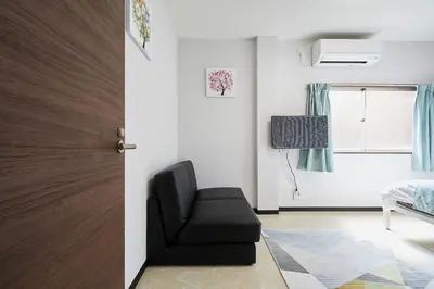 a living room with a black chair and a door at Mitsuba Guest House in Tokyo