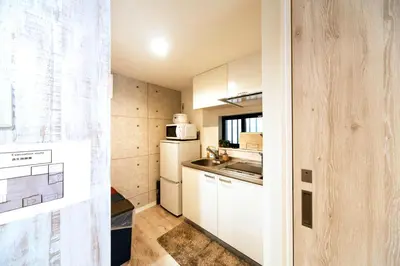 a small kitchen with white cabinets and a white refrigerator at nestay house tokyo itabashi 01 in Tokyo