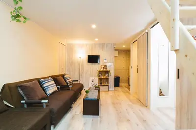 a living room with a brown couch and a tv at nestay house tokyo itabashi 01 in Tokyo