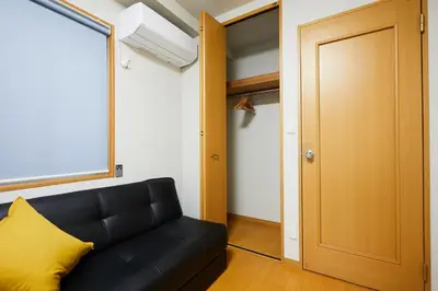 a living room with a black couch and a door at 22-Sweet Dreams House in JR Okubo Station 5 min in Tokyo