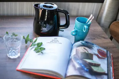 an open book on a table with a tea pot and a cup at Calm Asakusa Kaminarimon Gate CLx in Tokyo