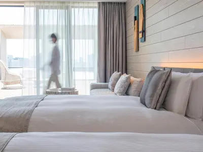 a hotel room with a bed and a man walking by a window at Mitsui Garden Hotel Jingugaien Tokyo Premier in Tokyo