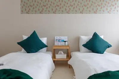 two beds with green pillows in a room at Tokyo Sunshine Tower Premium Hotel in Tokyo