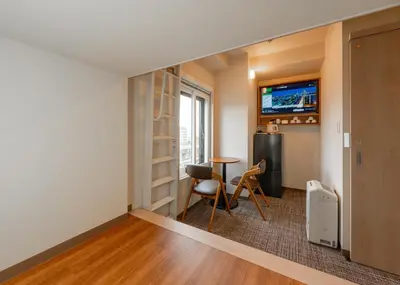 a small room with a table and a refrigerator at Tabist TOKYO CITY VIEW HOTEL in Tokyo