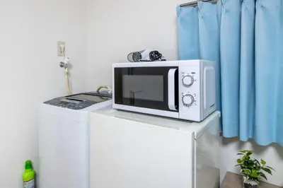 a microwave sitting on top of a refrigerator at Uhome Tabata Apartment in Tokyo