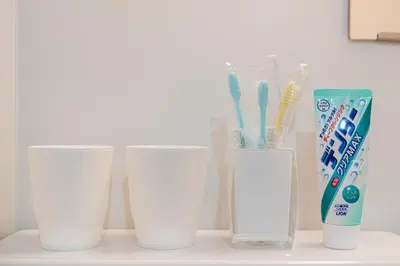 four white cups sitting on a counter with toothbrushes and toothpaste at Uhome Tabata Apartment in Tokyo