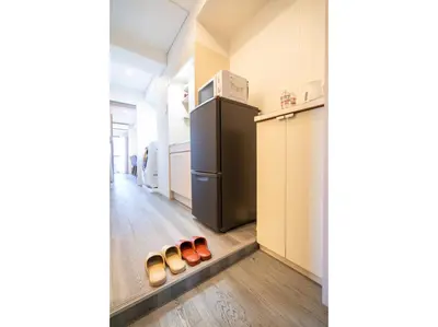a kitchen with a black refrigerator and a row of shoes at ZAITO Tokyo Kinshicho Economy Inn \u5b85\u4e1c\u4e1c\u4eac\u6a2a\u5ddd1\u6c11\u5bbf in Tokyo