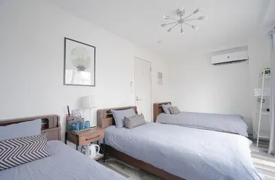 a bedroom with two beds and a clock on the wall at ZAITO Tokyo Kinshicho Economy Inn \u5b85\u4e1c\u4e1c\u4eac\u6a2a\u5ddd1\u6c11\u5bbf in Tokyo