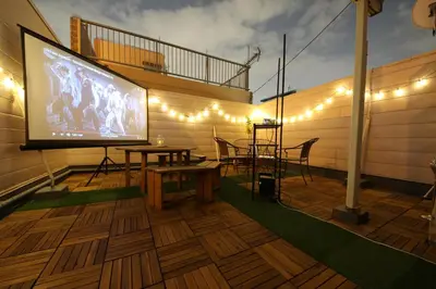 a large screen television on a patio with a table and chairs at Casa HANA in Tokyo