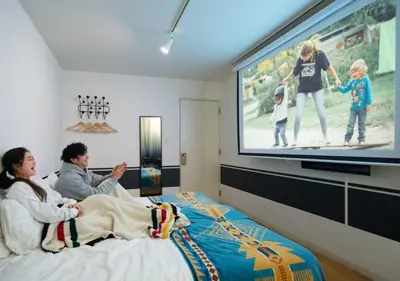 a group of people sitting on a bed watching a tv at Hotel Graphy Nezu in Tokyo