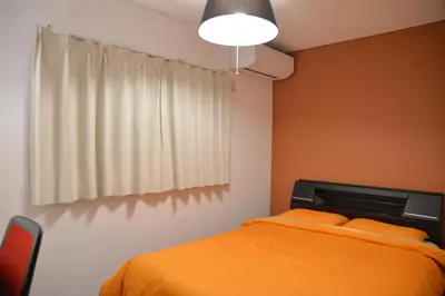 a bedroom with a bed with orange sheets and a window at K House in Tokyo