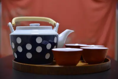 a polka dot tea pot and three cups on a table at K House in Tokyo