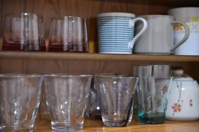 a row of empty glasses sitting on a shelf at K House in Tokyo