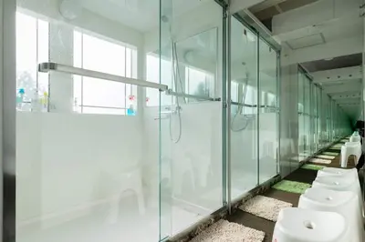 a row of toilets in a bathroom with glass walls at Hotel Adonis Tokyo - Dormitory Share Room For Male Only At City Center in Tokyo