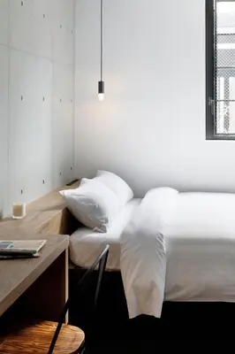 a bedroom with a bed with white sheets and a desk at HOTEL CEN in Tokyo