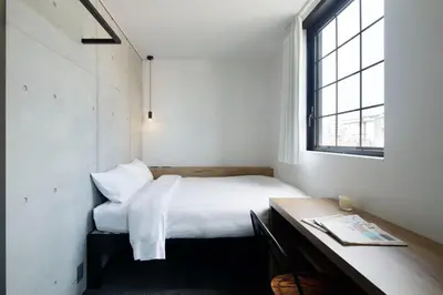 a bedroom with a bed and a desk and a window at HOTEL CEN in Tokyo