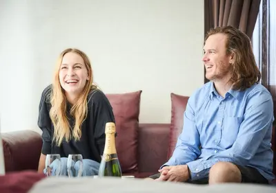 a man and woman sitting on a couch with a bottle of wine at Hotel Balian Resort Higashi Shinjuku in Tokyo