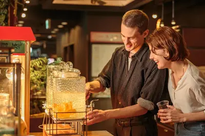a man and a woman standing behind a blender at Hotel Balian Resort Higashi Shinjuku in Tokyo
