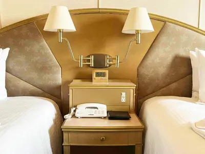 a hotel room with two beds and a phone on a night stand at Ginza Creston in Tokyo