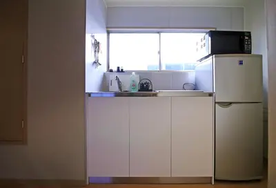 a small kitchen with a refrigerator and a microwave at Spacious Tokyo Apartment for 6-8 Guests!! 1 min to Morisita Station , Direct to Shinjuku in Tokyo