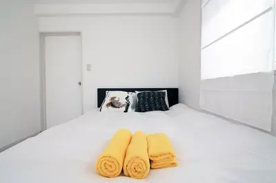 a bedroom with a white bed with two towels on it at Spacious Tokyo Apartment for 6-8 Guests!! 1 min to Morisita Station , Direct to Shinjuku in Tokyo