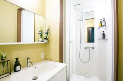 a bathroom with a sink and a shower with a mirror at Playsis Asakusa in Tokyo